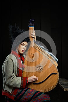 Gorgeous young woman in ukrainian traditional costume with ukrainian musical instrument bandura