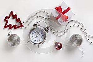 Gorisontal New year or Christmas holiday composition on white background. Gift box, New year balls, clock.