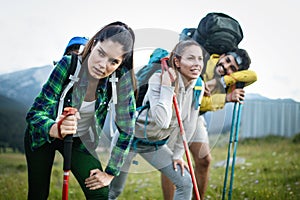 Gorup of friends climbing up hill, with backpacks and climbing stick