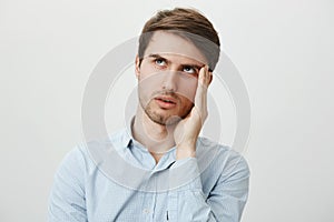 Gosh, so annoying, hope she would not talk to me. Portrait of bothered handsome young man in casual shirt holding palm