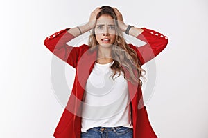 Gosh have trouble. Portrait of panicking worried young cute silly female trainee wearning red jacket holding hands head