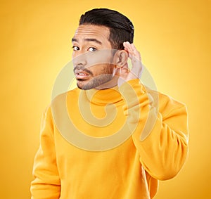 Gossip, whisper and man portrait with hand on ear in studio for speak up body language on yellow background. Secret