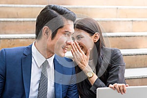 Gossip in the workplace. Business Woman whispering to colleague during work together. Man face is surprised about rumour