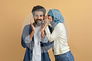 Gossips Concept. Muslim Woman In Hijab Whispering Secret To Her Surprised Boyfriend