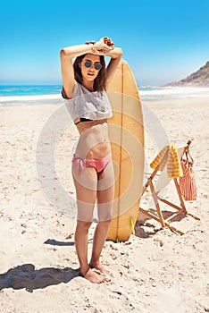 She got the body of a surfer. Portrait of a sexy young woman standing on the beach with her surfboard.