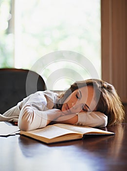 She got lost somewhere in between the pages. an attractive young woman enjoying a peaceful nap at home with a book in