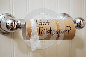 `Got Toilet Paper`, written in sharpie on cardboard toilet paper roll that is left hanging on the spool, on the wall