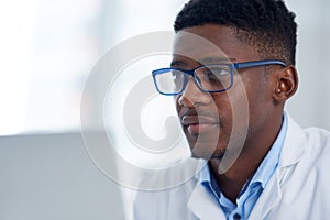 he got a whole lot of brains. a focused young male scientist working on his laptop while being seated inside of a