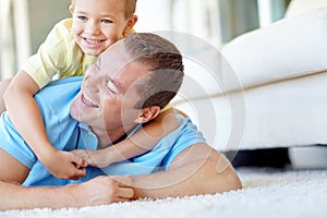 Got you, dad. Young boy and his father wrestling playfully in the lounge.