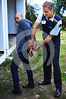 Gotcha. Full length shot of a man being handcuffed by a police officer.