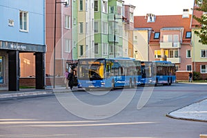 Two blue buses waiting for passengers at colorful houses in Amhult..