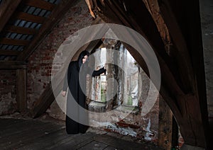 Gothic brunette woman standing near the window in attic