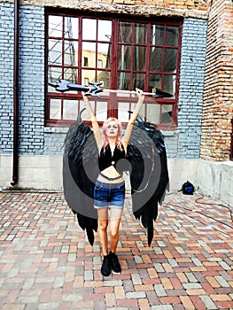 Gothic girl with huge black wings holding up a sword