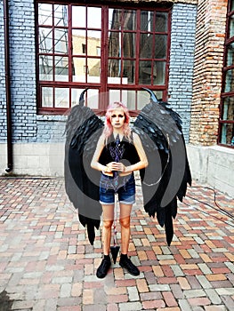 Gothic girl with huge black wings holding up a sword
