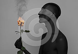 Gothic and Halloween theme: a man with black skin holding a red rose, black death isolated on a gray background in studio