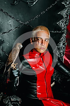 Gothic man with scary bloody makeup and bird of prey on huge scary throne ready for Halloween party