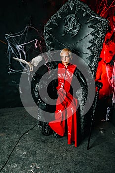 Gothic man with scary bloody makeup and bird of prey on huge scary throne ready for Halloween party
