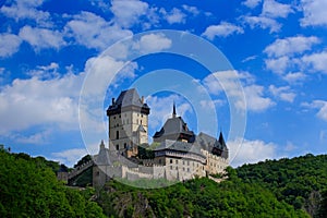 Gothic royal castle Karlstejn in green forest during summer with blue sky and white clouds, Central Bohemia, Czech republic, Europ