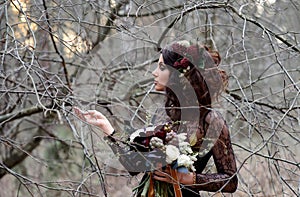 A Gothic woman in a black dress with dark makeup with flowers in her hair in a mysterious forest. Magic black, Gothic beauty,