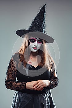 Gothic young woman in witch halloween costume with hat standing