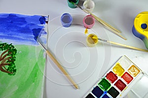 gouache paint brushes and children's drawings. photo child paints a brush with watercolor honey paints. children's art