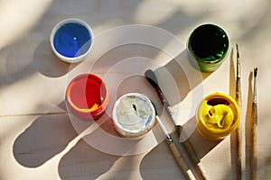 Gouache paint open jars stand on a wooden surface, top view