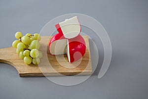 Gouda cheese with grapes on chopping board