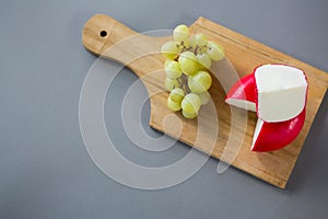 Gouda cheese with grapes on chopping board