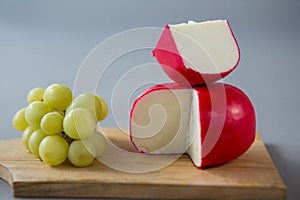 Gouda cheese with grapes on chopping board