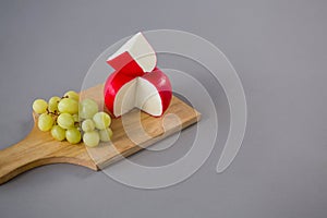 Gouda cheese with grapes on chopping board