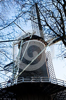Gouda, South Holland/the Netherlands - January 20 2019: Picture of old windmill next to city park taken through tree branches