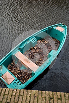 Gouda, South Holland/the Netherlands - March 1 2020: Old green and blue boat floating in the canal filled with rain water and old