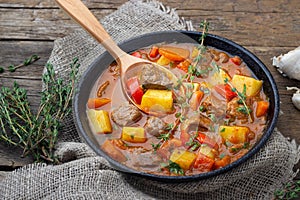 Goulash, beef stew or bogrash soup with meat, vegetables and spices in cast iron pan.