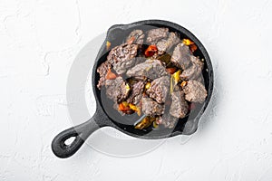 Goulash, beef stew, in cast iron frying pan, on white stone  surface, top view flat lay