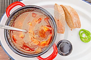 goulash soup served in red casserole with species and bread