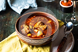 Goulash or stew in copper pan with spoon on rustic kitchen table. Eintopf, chili con carne. Traditional hungarian dish. Homemade