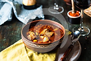 Goulash or stew in copper pan with spoon on rustic kitchen table. Eintopf, chili con carne. Traditional hungarian dish. Homemade photo