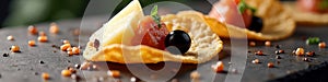 Gourmet appetizer with cheese, tomato, and black olive on crispy cracker