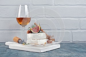 Gourmet appetizer of white brie cheese or camembert with fresh figs, nuts and glass of wine for tasting