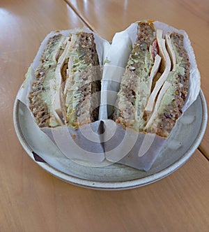 Vegan tofu sandwich wraped in paper served on saucer photo
