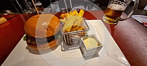 Gourmet burger and fries with beer on table