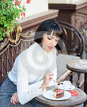 Gourmet concept. Delicious gourmet cake. Woman attractive brunette eat gourmet cake cafe terrace background