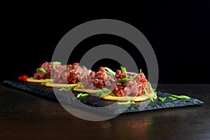 Gourmet delicacy raw meat starter on black slate.