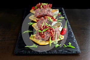 Gourmet delicacy raw meat starter on black slate.