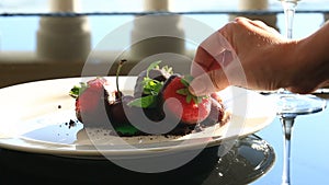 This is a gourmet dish. close-up. Dessert, strawberry in chocolate. With a glass of white wine. Seaside restaurant with