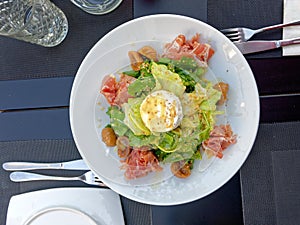 Gourmet green salad plate served with prosciutto and ricotta white cheese