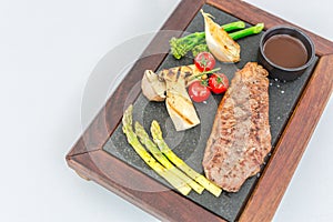 Gourmet grill menu. Beef steak grilled with vegetables on cutting board at dark background. Barbecue dish. Top view with copyspace