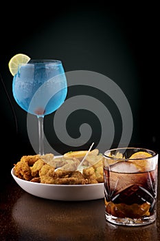 gourmet happyhour - fish and chips, negroni and blue curacao on wooden table