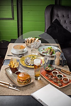 Gourmet meals assorted set steak burger fish salad beer on wooden table Buffet at restaurant