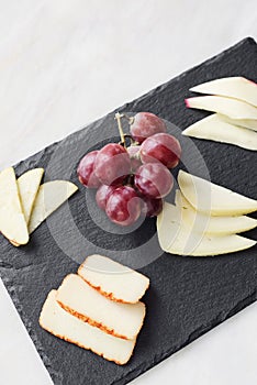Gourmet mixed cheese board tapas starter with apple and grapes